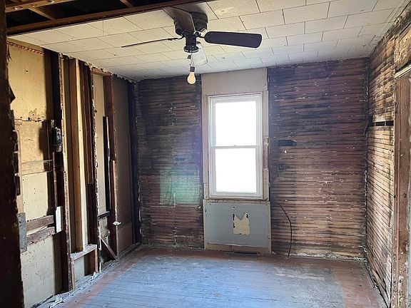 An empty room with a ceiling fan and a window.