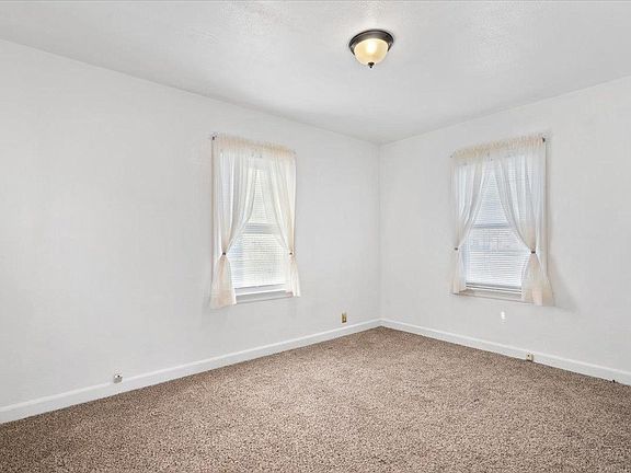 An empty bedroom with two windows and a ceiling light.