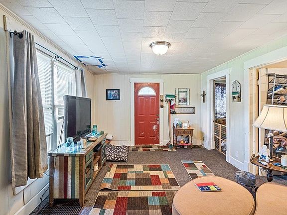 A living room with a red door and a flat screen tv.