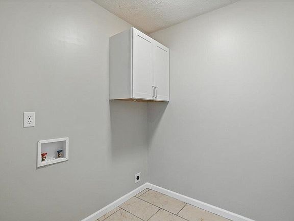 An empty laundry room with a white cabinet on the wall.