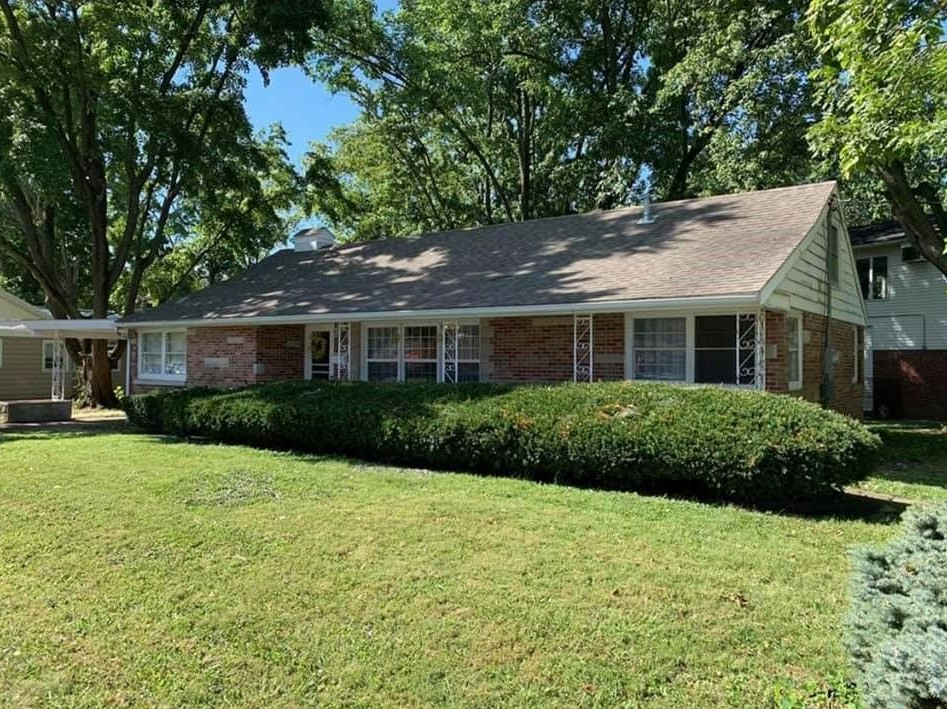 A large brick house with a large lawn in front of it.