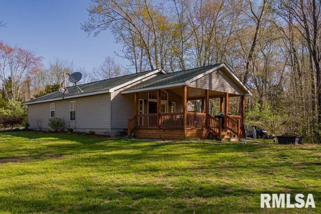 A mobile home with a porch and a satellite dish on the roof is for sale.
