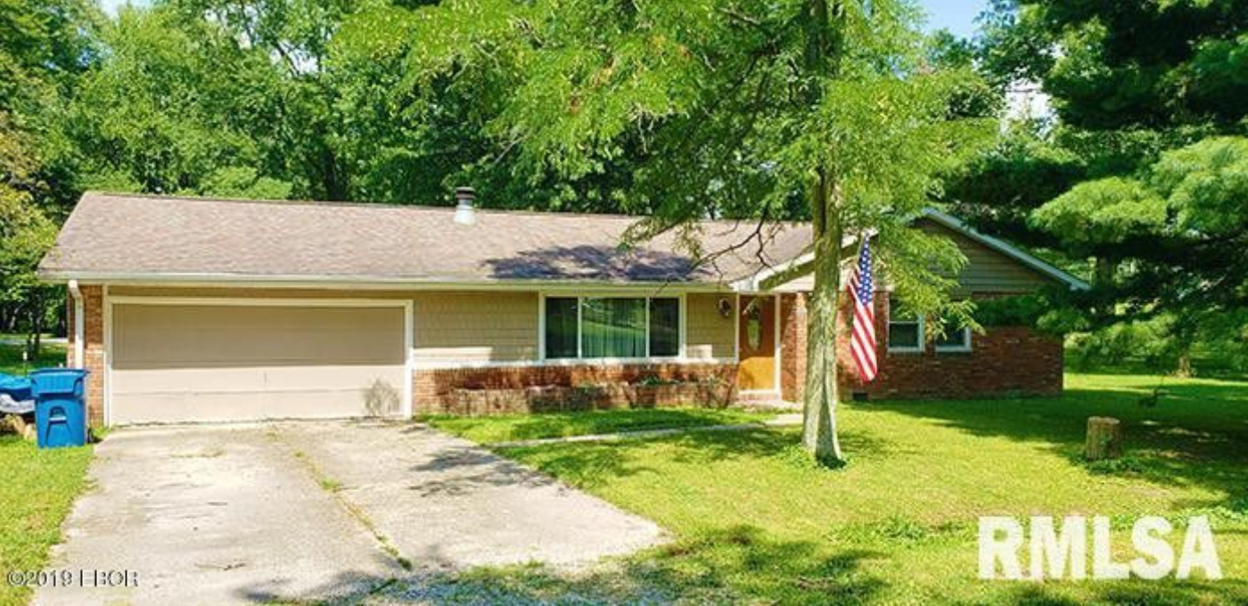 A house with a garage and an american flag in front of it.
