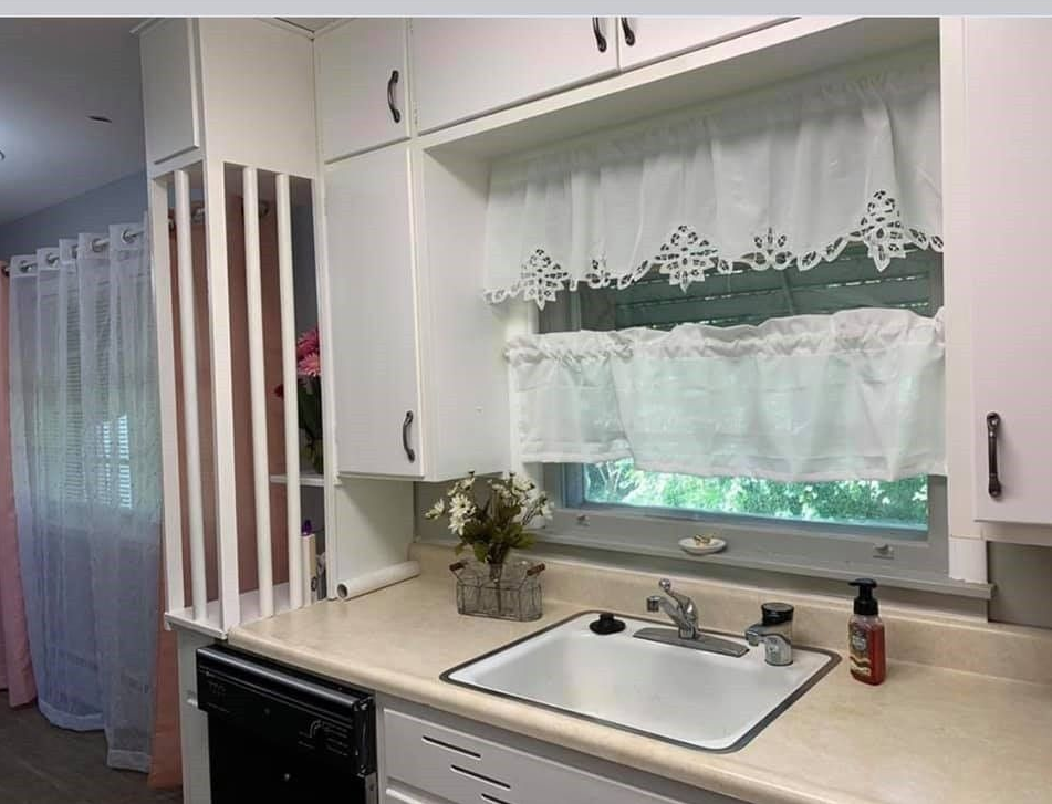 A kitchen with a sink , dishwasher , and window.