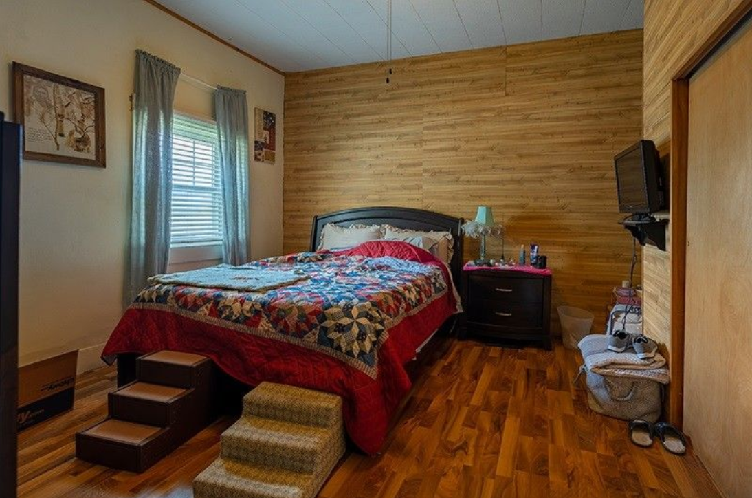 A bedroom with a bed , nightstand , and television.