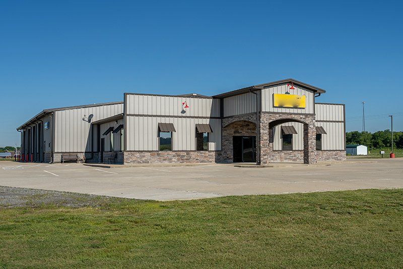 A large building with a lot of windows is sitting on top of a lush green field.