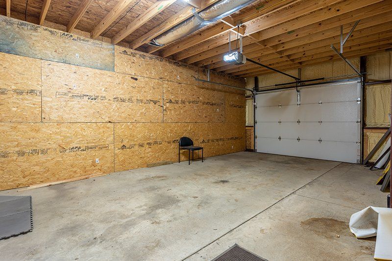There is a chair in the garage with a garage door open.