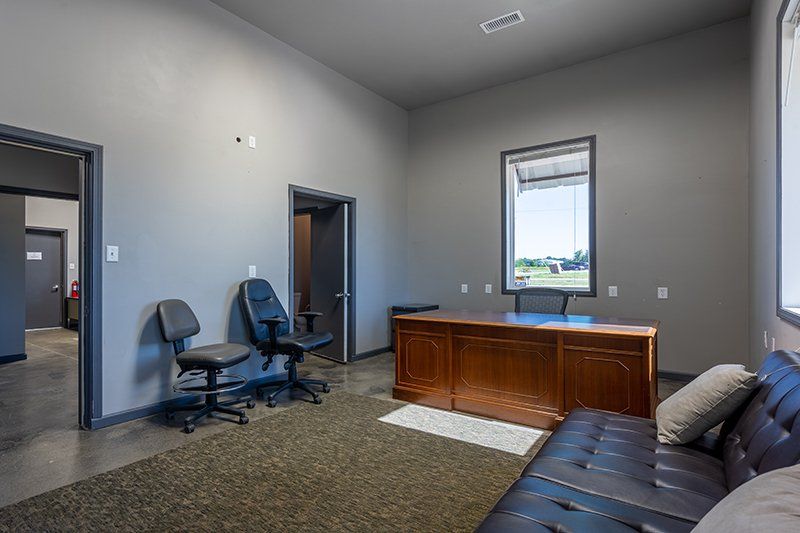 A living room with a couch , desk , chairs and a window.