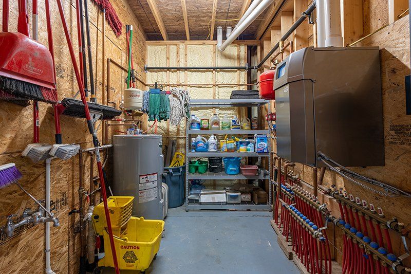 A utility room with a water heater , mop , and cleaning supplies.