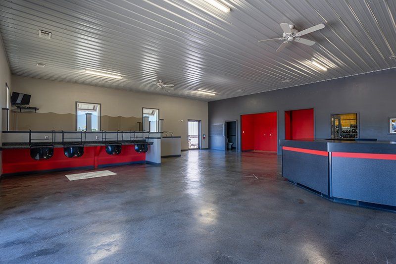 A large empty room with a ceiling fan and a reception desk.