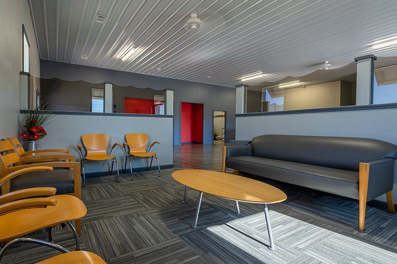 A waiting room with a couch , chairs , and a coffee table.