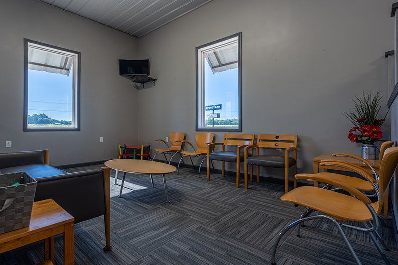 A waiting room with chairs , tables , and a television.