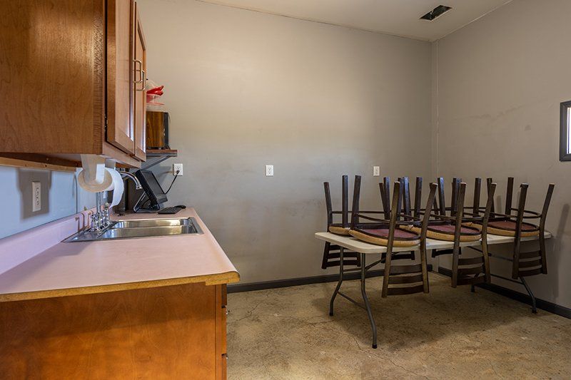 A kitchen with a sink , table and chairs.