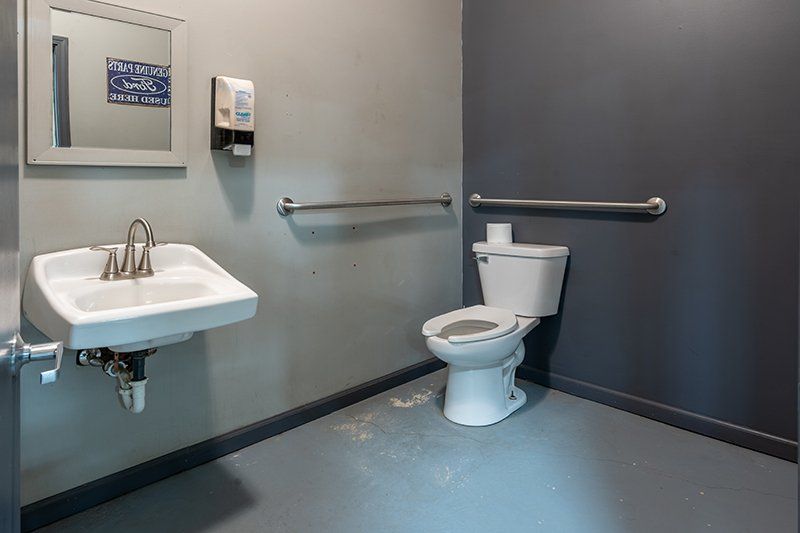 A bathroom with a toilet , sink and mirror.
