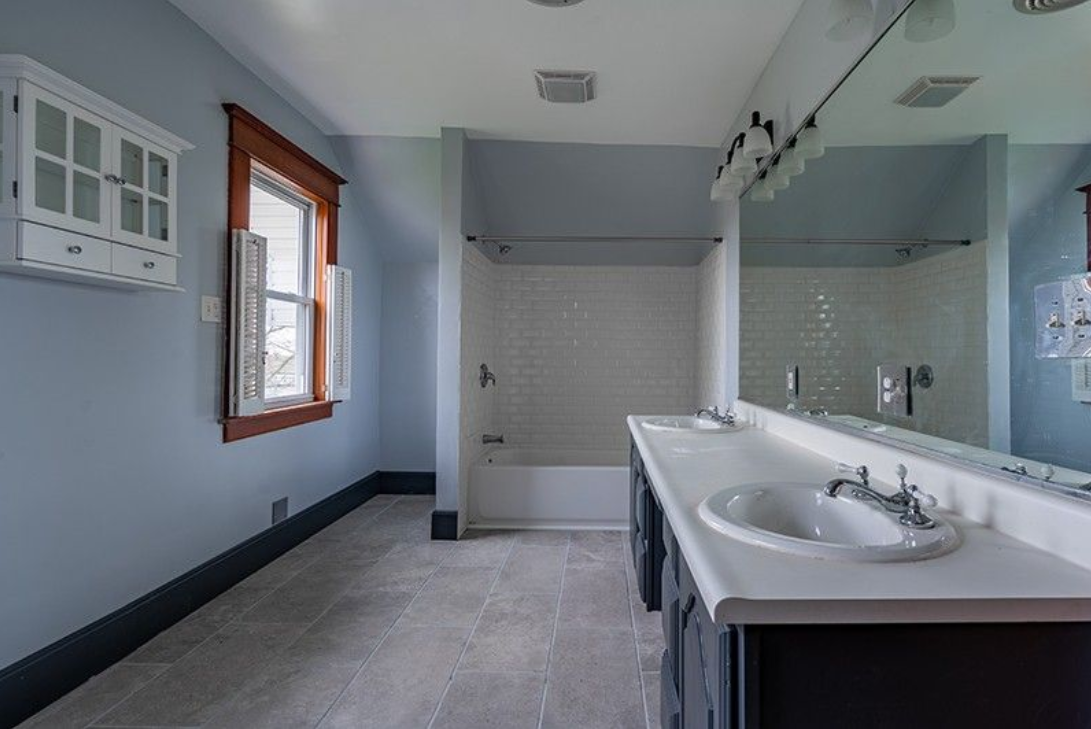 A bathroom with two sinks , a tub and a mirror.
