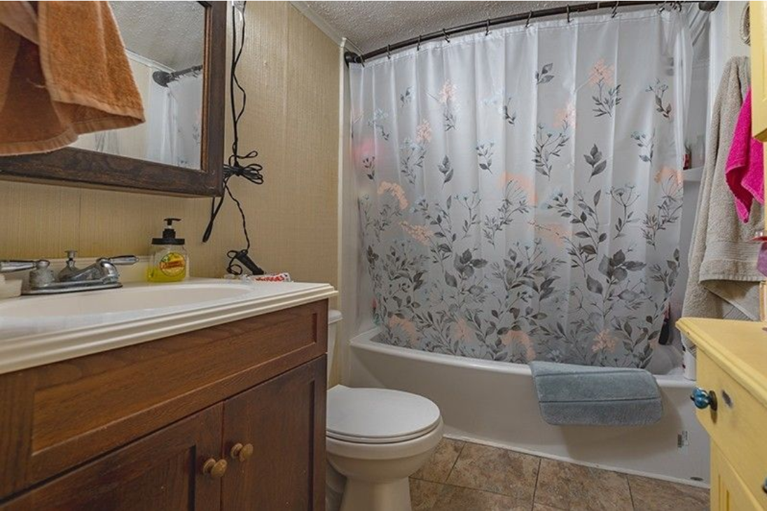 A bathroom with a toilet , sink , and shower curtain.