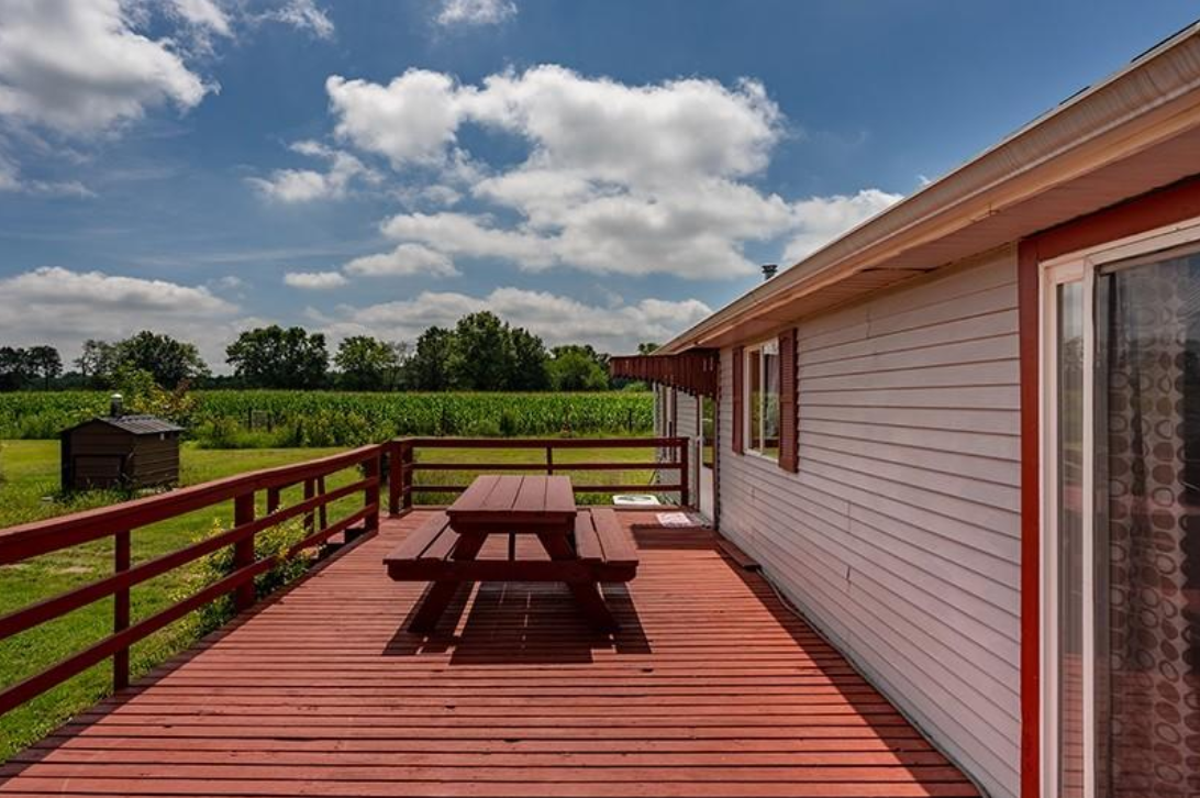 There is a picnic table on the deck of a house.