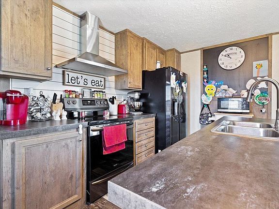 A kitchen with a stove , refrigerator , sink and a sign that says `` let 's eat ''.