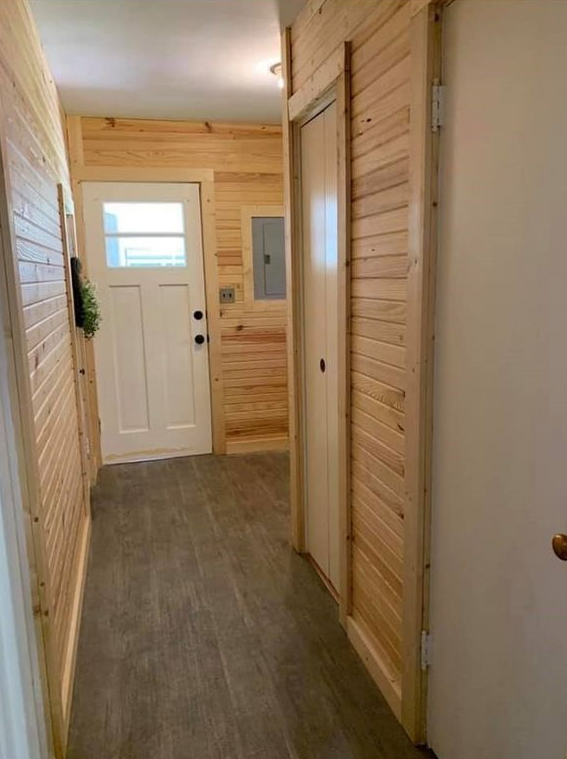 A hallway with wood paneling and a door in a cabin.