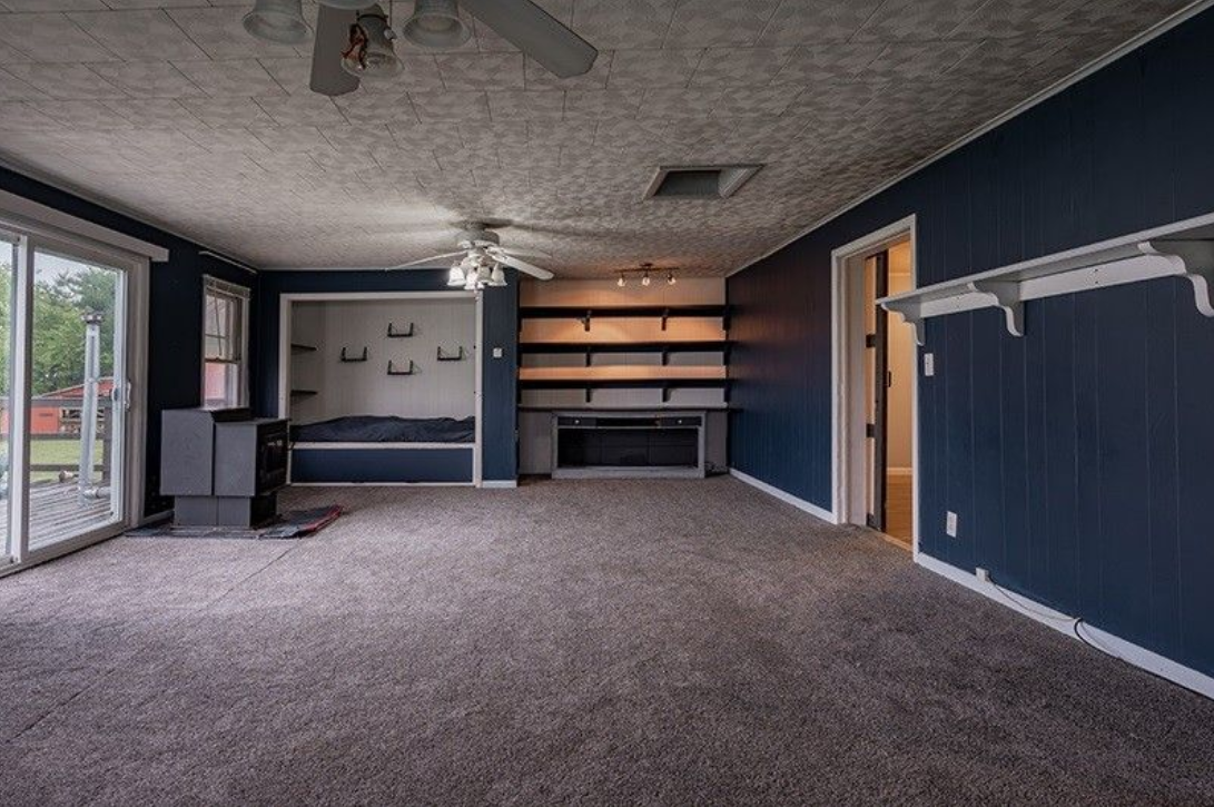 An empty living room with blue walls and a ceiling fan.