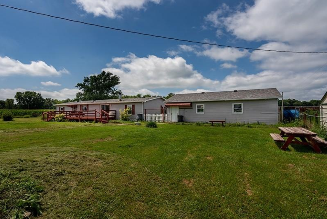 A picnic table is in the grass in front of a house.