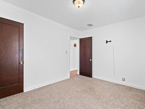 An empty bedroom with a carpeted floor and two doors.