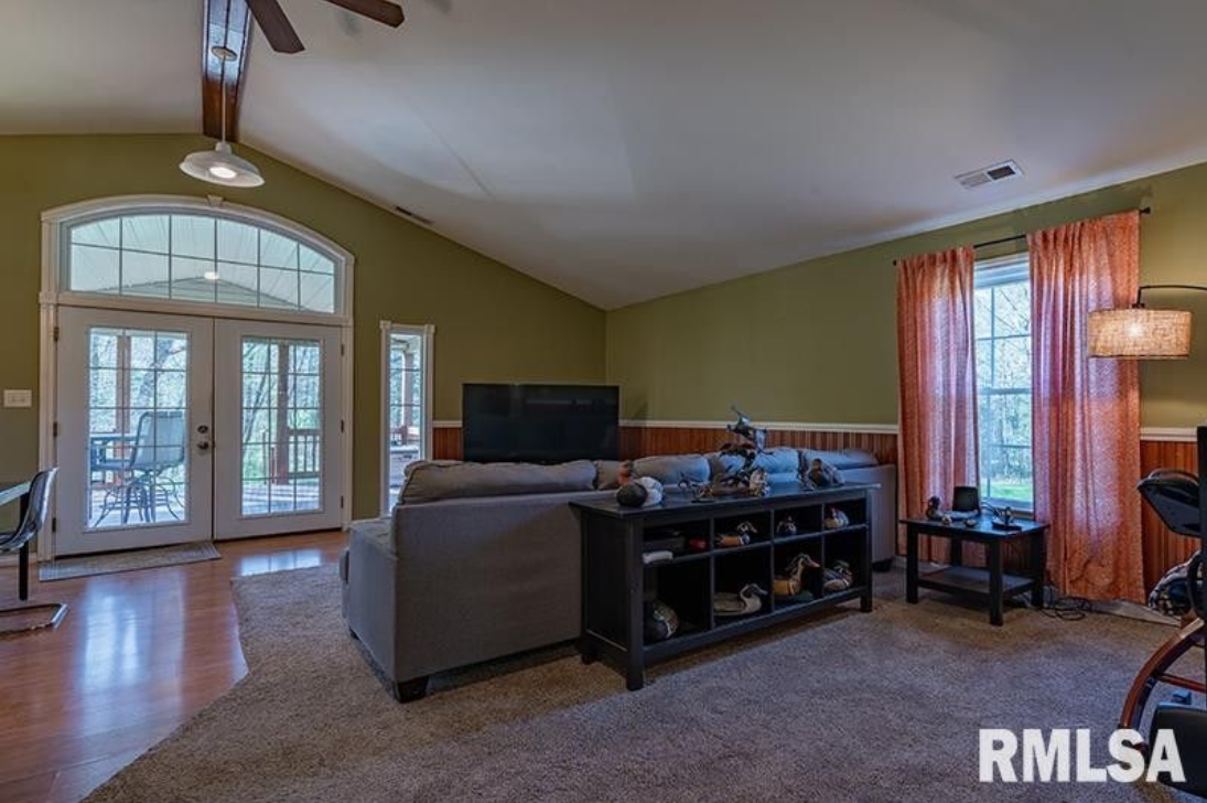 A living room with a couch , television , and a ceiling fan.