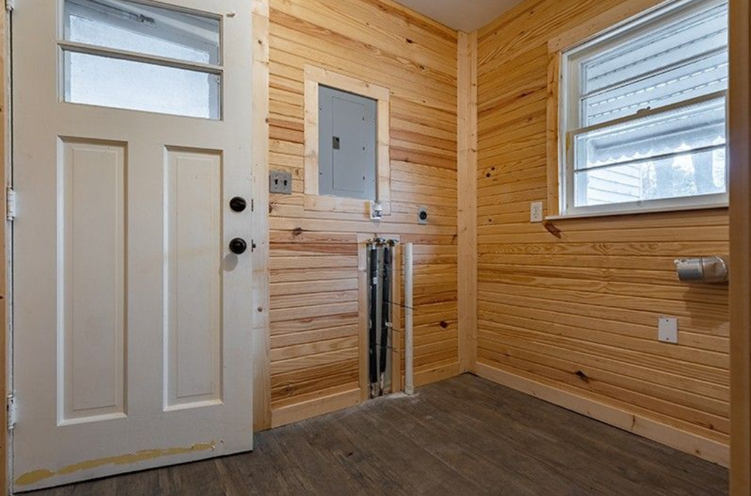 A room with wooden walls and a white door.