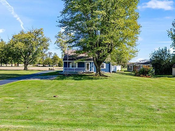A blue house with a large lawn in front of it.
