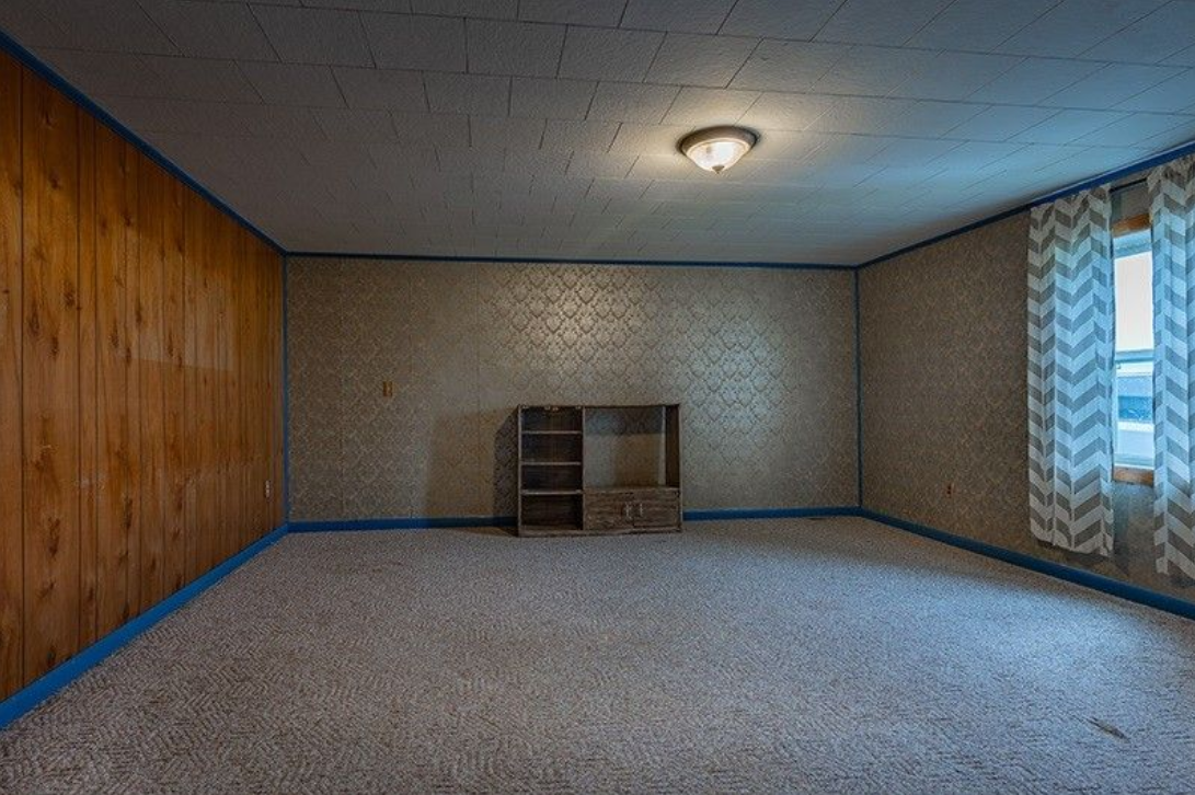 An empty room with wood paneling and a carpeted floor.