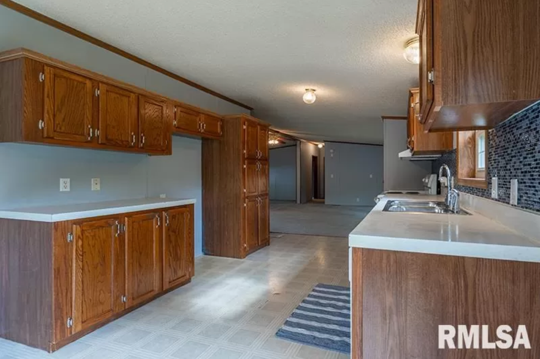 An empty kitchen with wooden cabinets and a sink.