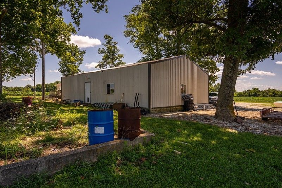 A large white building is sitting in the middle of a grassy field.