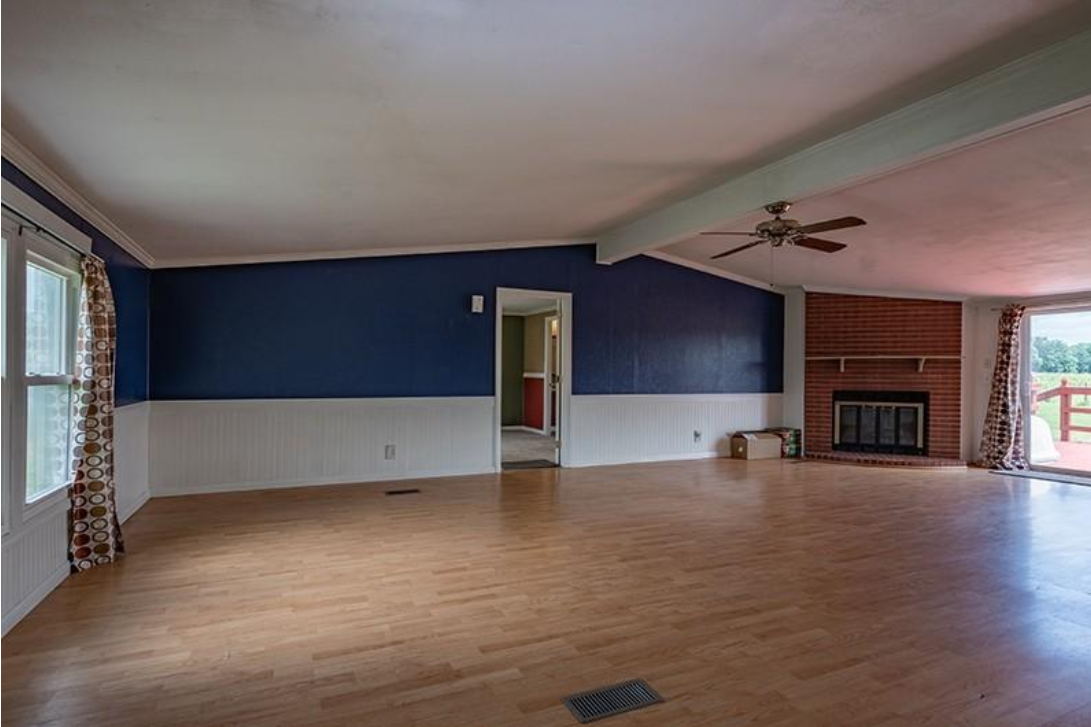 An empty living room with hardwood floors , blue walls and a fireplace.