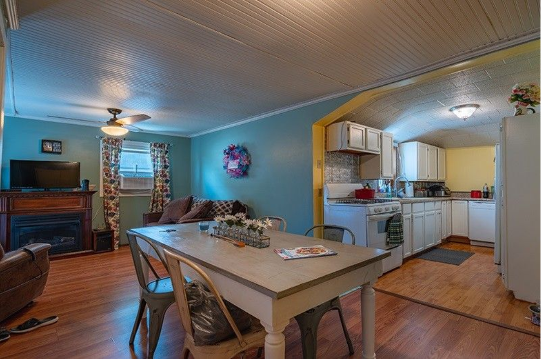 A living room with a table and chairs and a kitchen.