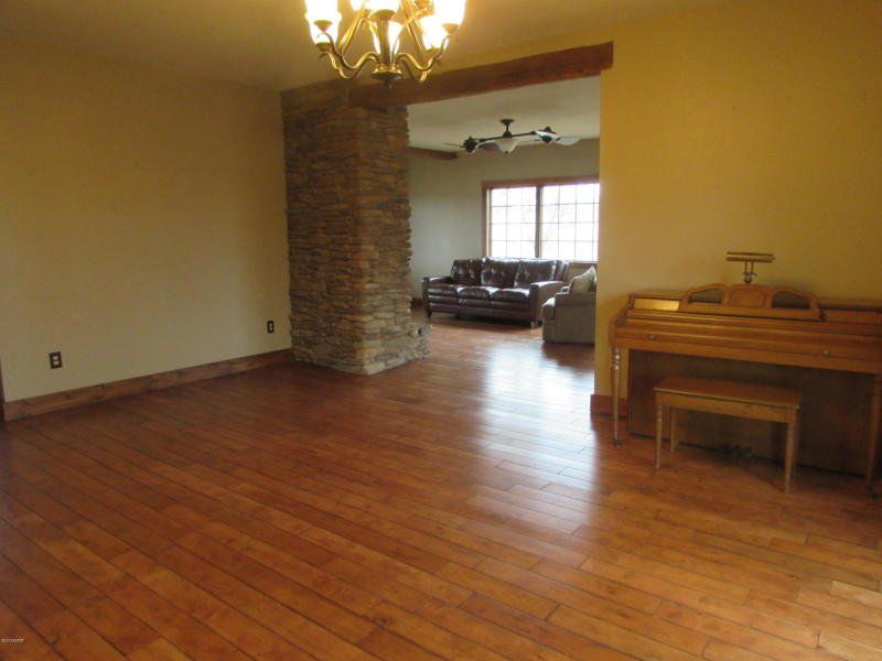 An empty living room with hardwood floors and a piano.