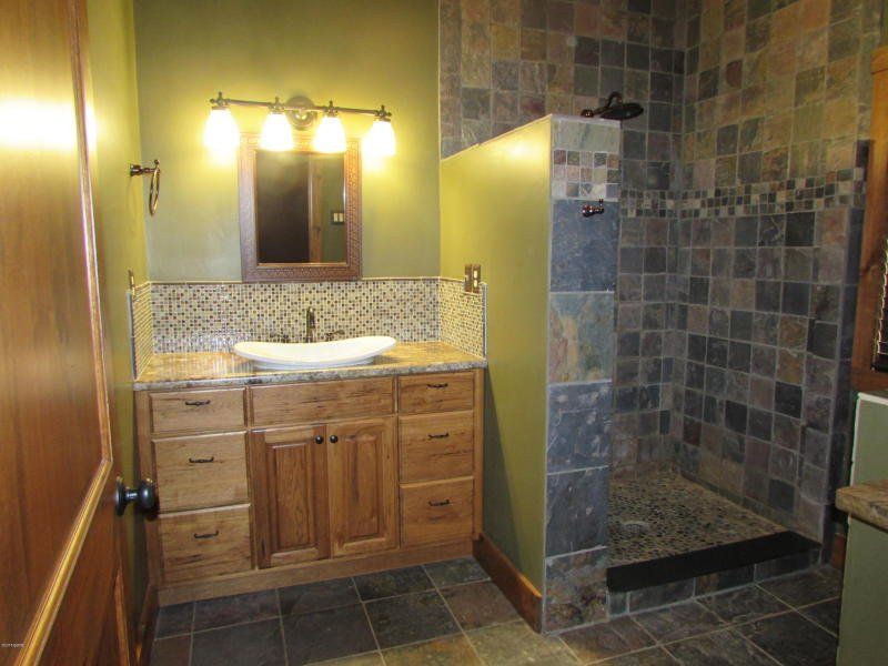 A bathroom with a sink , mirror , and walk in shower.