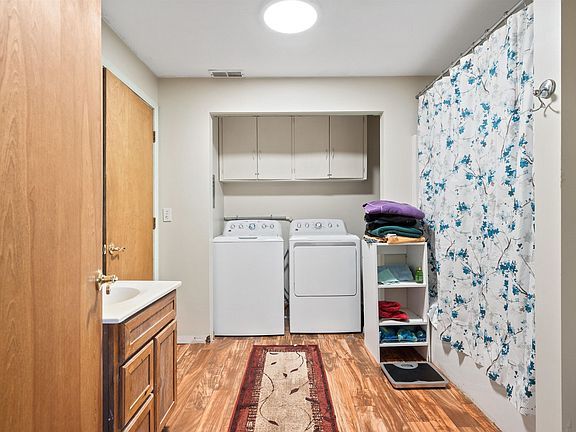 A bathroom with a sink , washer and dryer , and shower curtain.