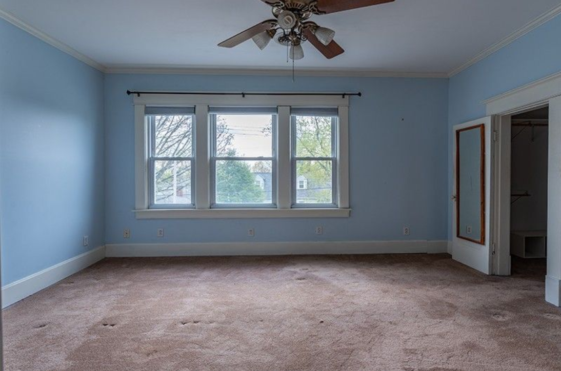 An empty room with blue walls and a ceiling fan.