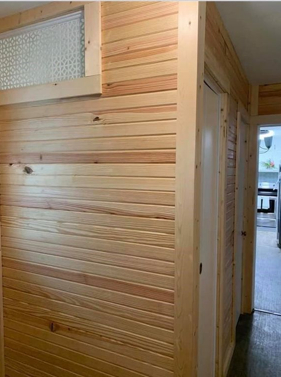 A hallway with wood paneling and a window.