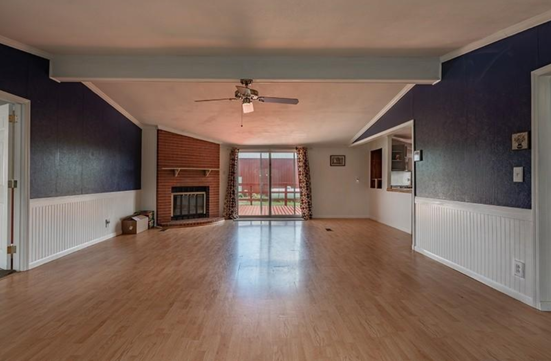 An empty living room with hardwood floors and a fireplace.