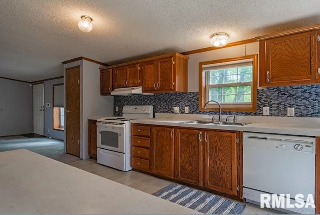 A kitchen with wooden cabinets , a stove , a sink , and a dishwasher.