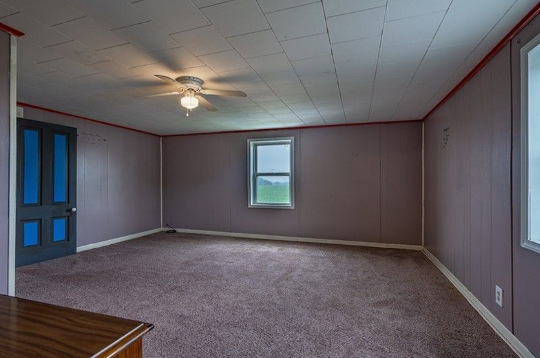 An empty room with a ceiling fan and a window