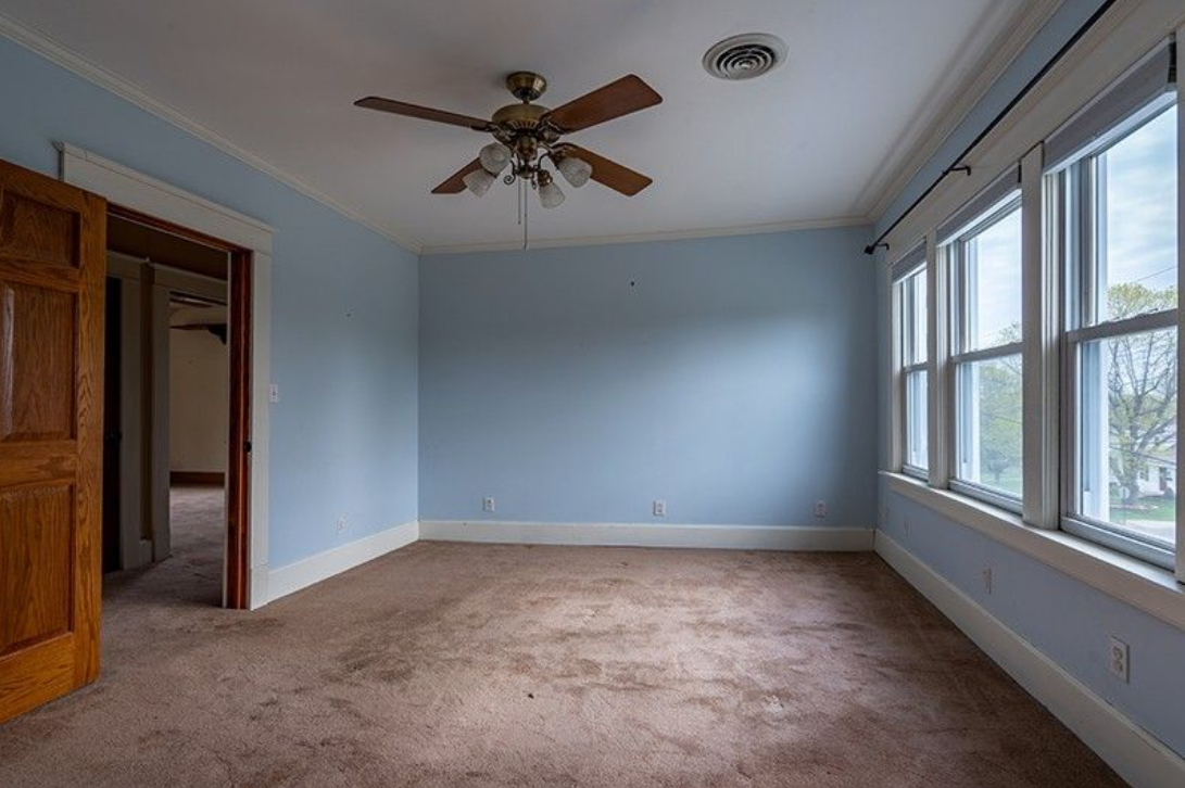 An empty room with a ceiling fan and a lot of windows.