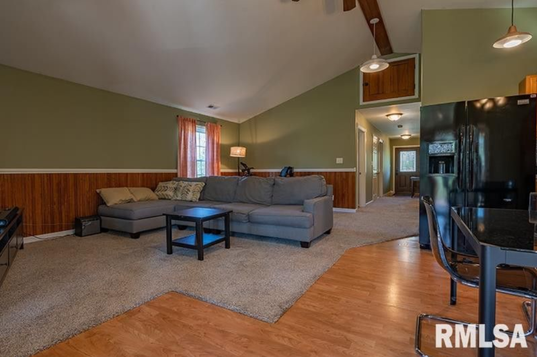 A living room with a couch , table , chairs and a refrigerator.