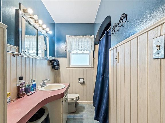 A bathroom with a sink , toilet , mirror and shower curtain.