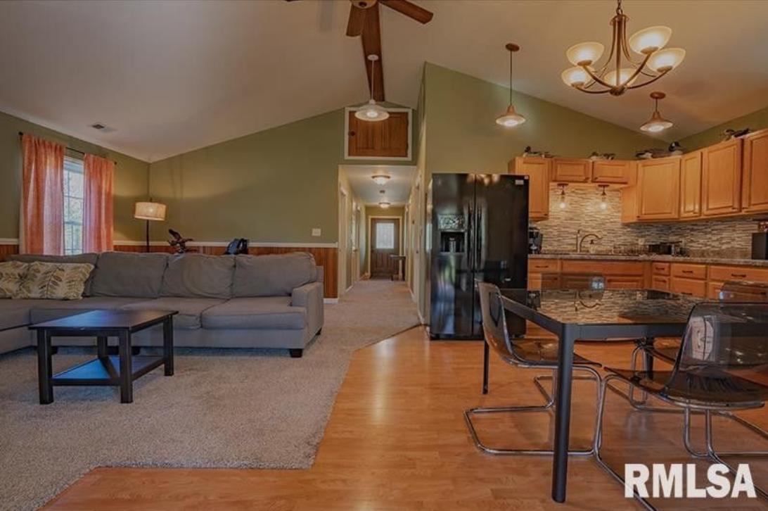 A living room with a couch , table , chairs and a refrigerator.