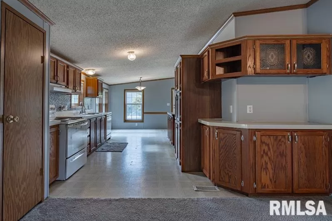 A kitchen with wooden cabinets and stainless steel appliances in a mobile home.