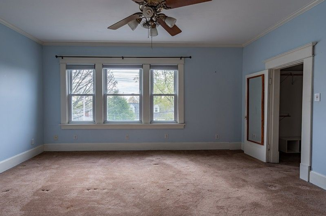 An empty room with blue walls and a ceiling fan.