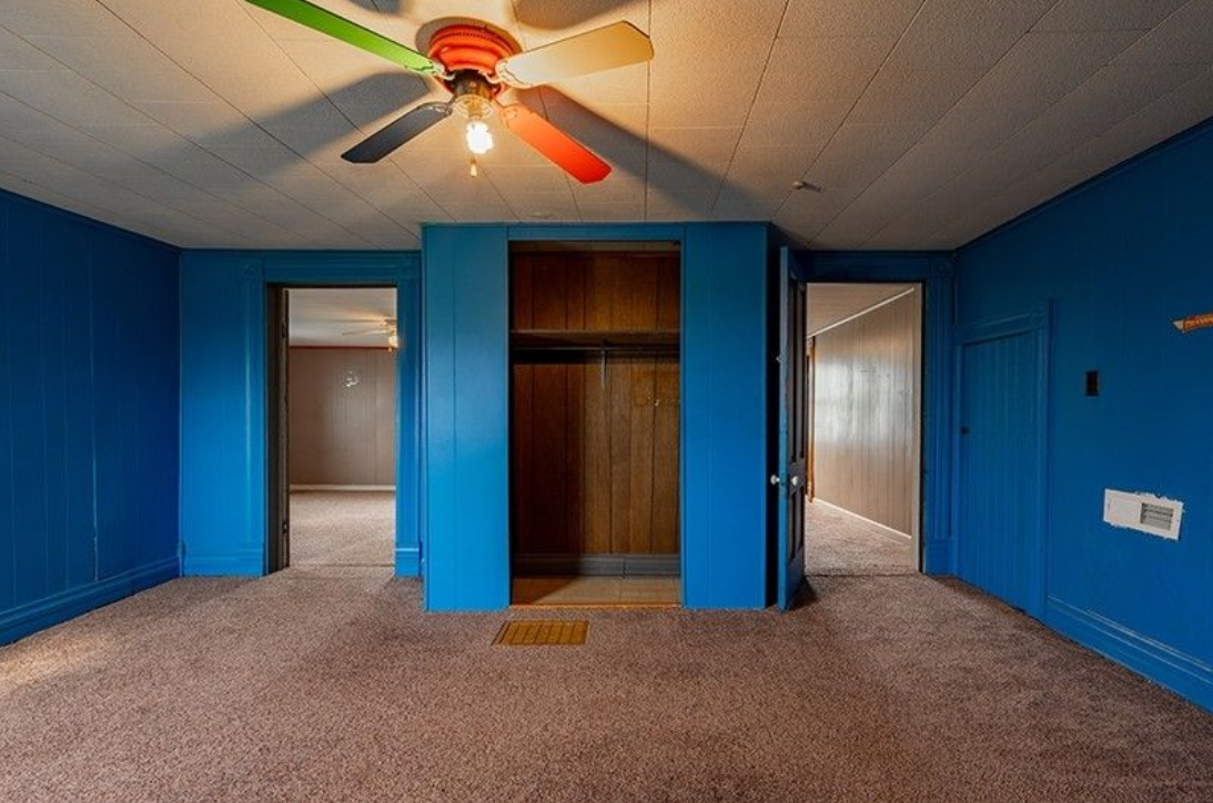 An empty room with blue walls and a ceiling fan