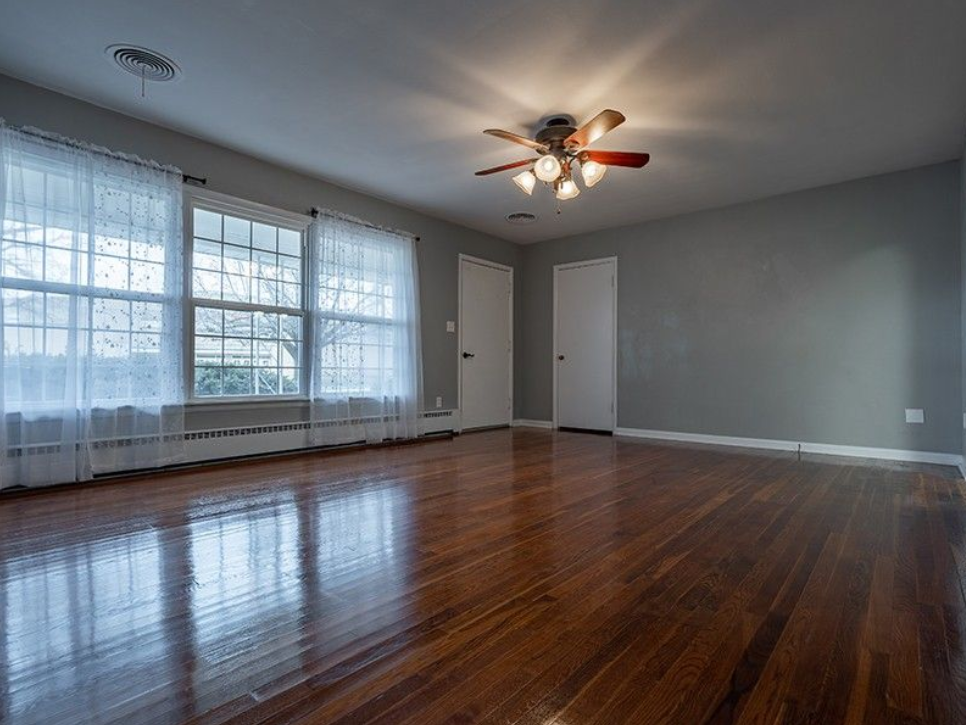An empty living room with hardwood floors and a ceiling fan.